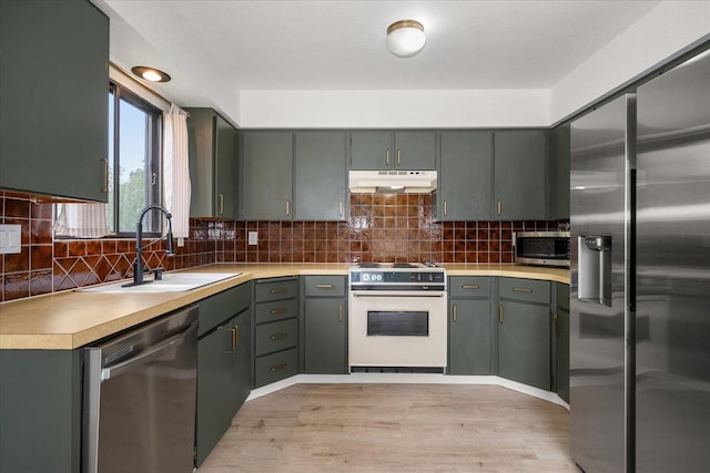20716 E Gilbert Rd, Otis Orchards, WA 99027 - kitchen with appliances with stainless steel finishes, under cabinet range hood, a sink, light wood-type flooring, and light countertops
