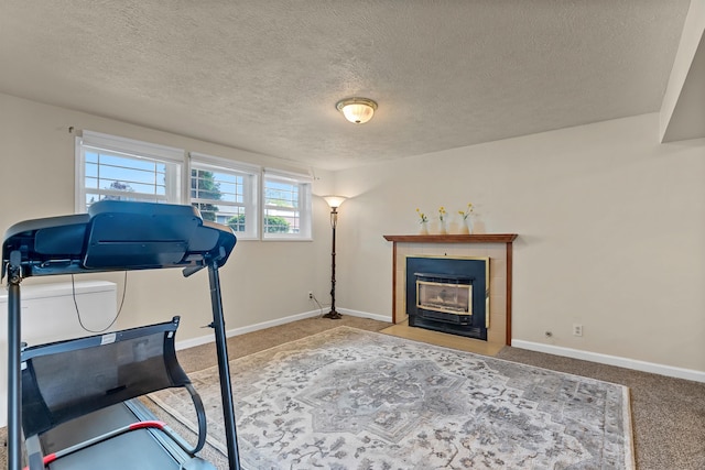 4022 E 25th Ave, Spokane, WA 99223 - workout area featuring a tiled fireplace, carpet, a textured ceiling, and baseboards