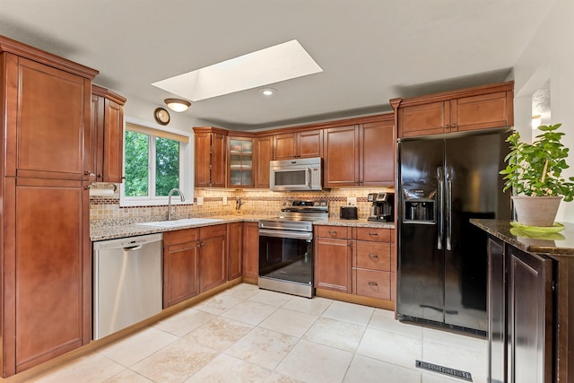 4022 E 25th Ave, Spokane, WA 99223 - kitchen featuring stainless steel appliances, a sink, a skylight, light stone counters, and tasteful backsplash