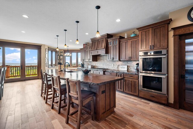 16510 N Brannon Ln, Spokane, WA 99208 - kitchen featuring stainless steel appliances, a kitchen island with sink, a sink, light wood finished floors, and recessed lighting
