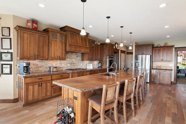 16510 N Brannon Ln, Spokane, WA 99208 - kitchen featuring a sink, stainless steel appliances, light wood-style floors, a kitchen bar, and brown cabinets