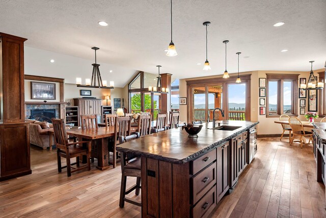 16510 N Brannon Ln, Spokane, WA 99208 - kitchen with a sink, dark countertops, light wood-style flooring, a glass covered fireplace, and dark brown cabinetry