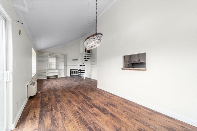 707 W 6th Ave Unit 41, Spokane, WA 99204 - unfurnished living room with ornamental molding, wood finished floors, vaulted ceiling, a wall mounted air conditioner, and baseboards