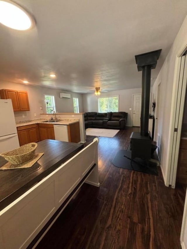 1108 Basin Rd, Colville, WA 99114 - kitchen with white appliances, a sink, dark wood-style floors, a wood stove, and healthy amount of natural light