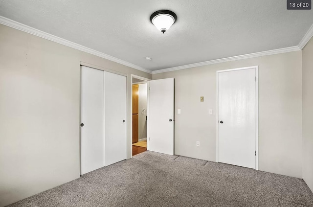 6015 E 6th Ave Apt N2, Spokane Valley, WA 99212 - unfurnished bedroom with carpet flooring, crown molding, a closet, and a textured ceiling