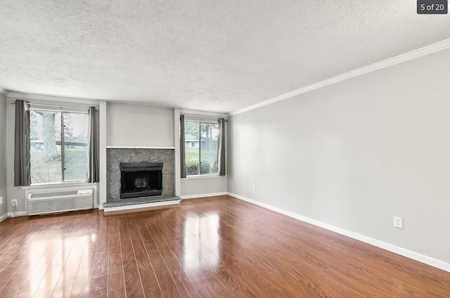 6015 E 6th Ave Apt N2, Spokane Valley, WA 99212 - unfurnished living room with a textured ceiling, wood finished floors, an AC wall unit, baseboards, and a stone fireplace