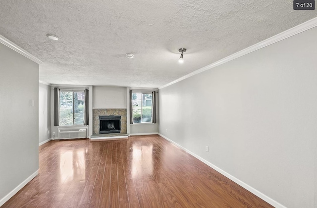 6015 E 6th Ave Apt N2, Spokane Valley, WA 99212 - unfurnished living room featuring wood finished floors, a textured ceiling, baseboards, a stone fireplace, and crown molding