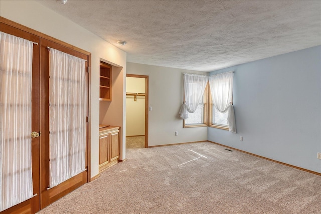 3023 S Winthrop Ln, Spokane, WA 99203 - unfurnished bedroom with a textured ceiling, baseboards, light colored carpet, and french doors
