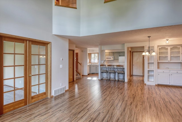 3023 S Winthrop Ln, Spokane, WA 99203 - unfurnished living room featuring a chandelier, light wood-type flooring, a high ceiling, stairway, and baseboards