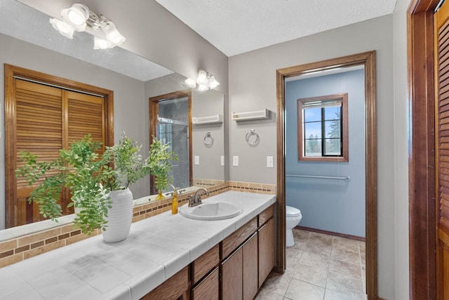 2311 S Mamer Ct, Spokane Valley, WA 99216 - bathroom with toilet, vanity, baseboards, and tasteful backsplash