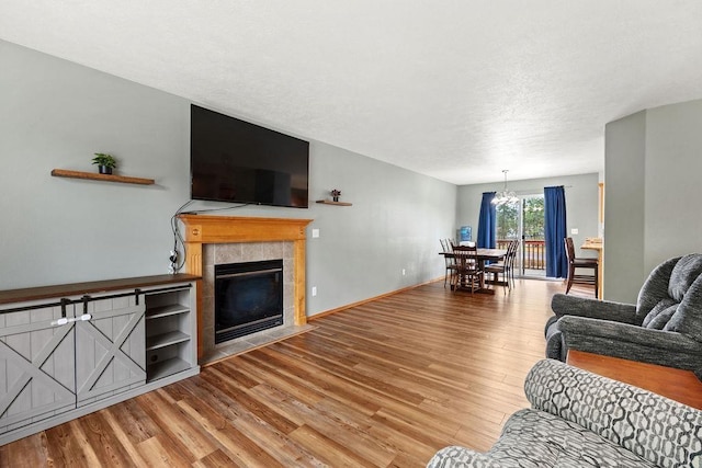 6831 N Cambridge Ln, Spokane, WA 99208 - living area with wood finished floors, a chandelier, a tile fireplace, a textured ceiling, and baseboards