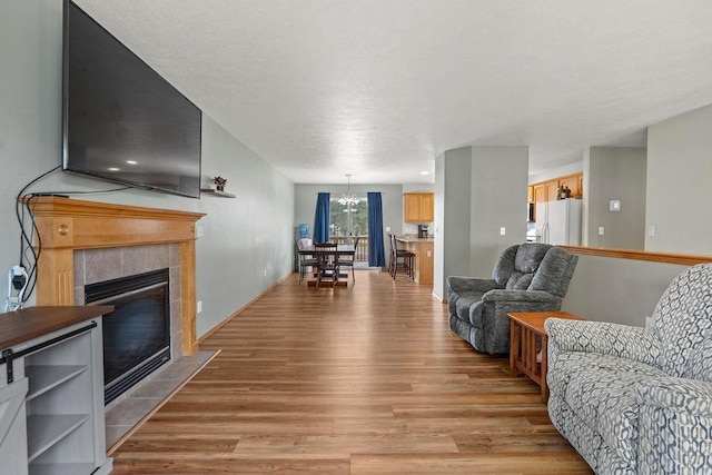 6831 N Cambridge Ln, Spokane, WA 99208 - living room featuring light wood finished floors, a chandelier, and a tiled fireplace