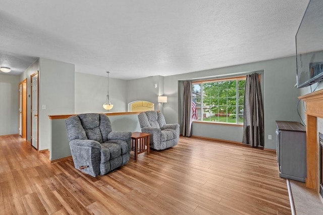 6831 N Cambridge Ln, Spokane, WA 99208 - living room featuring light wood-style flooring, a textured ceiling, baseboards, and a fireplace