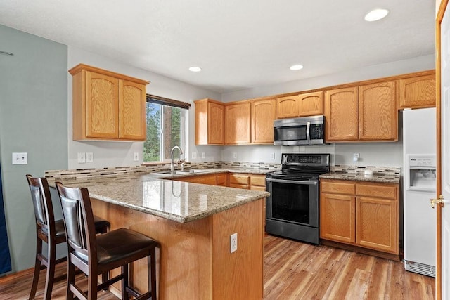 6831 N Cambridge Ln, Spokane, WA 99208 - kitchen featuring stainless steel appliances, a sink, a peninsula, light stone counters, and a kitchen breakfast bar