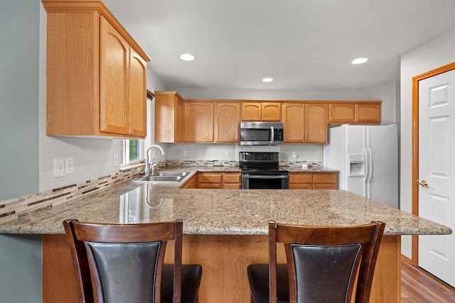 6831 N Cambridge Ln, Spokane, WA 99208 - kitchen with appliances with stainless steel finishes, a sink, a peninsula, light stone countertops, and recessed lighting