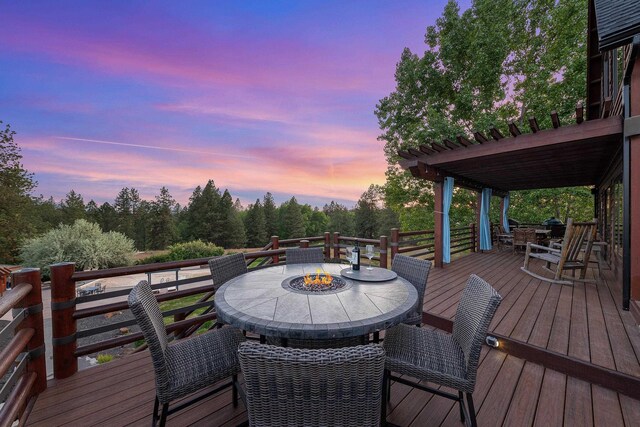 16010 W Jade Ln, Medical Lake, WA 99022 - deck at dusk with outdoor dining area, an outdoor fire pit, and view of wooded area