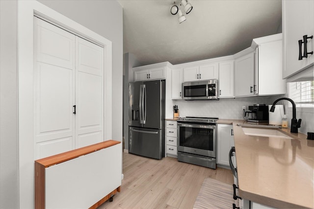3815 E 19th Ave, Spokane, WA 99223 - kitchen featuring appliances with stainless steel finishes, a sink, light wood-style flooring, white cabinetry, and light countertops