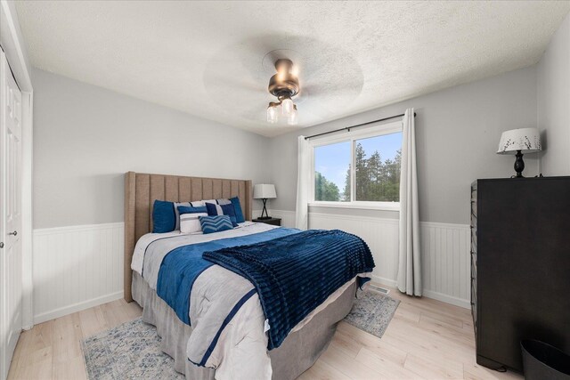 3815 E 19th Ave, Spokane, WA 99223 - bedroom with a wainscoted wall, light wood-style flooring, ceiling fan, and a textured ceiling