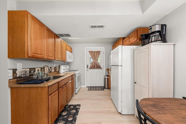 3815 E 19th Ave, Spokane, WA 99223 - kitchen with white appliances, a sink, light wood finished floors, brown cabinetry, and light countertops