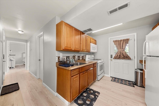 3815 E 19th Ave, Spokane, WA 99223 - kitchen with white appliances, a sink, light wood-style floors, and baseboards