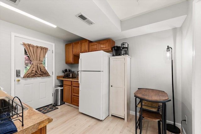 3815 E 19th Ave, Spokane, WA 99223 - kitchen with freestanding refrigerator, brown cabinetry, light wood-type flooring, and light countertops