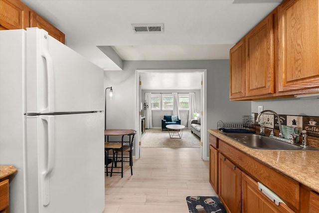 3815 E 19th Ave, Spokane, WA 99223 - kitchen with freestanding refrigerator, a sink, brown cabinets, light wood-type flooring, and light countertops