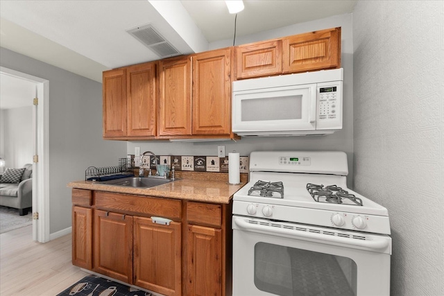 3815 E 19th Ave, Spokane, WA 99223 - kitchen featuring white appliances, a sink, light wood-type flooring, and brown cabinets