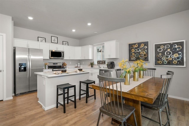 3286 N Glenrose Rd, Spokane, WA 99217 - kitchen featuring appliances with stainless steel finishes, white cabinets, light wood-style flooring, a kitchen island, and light countertops