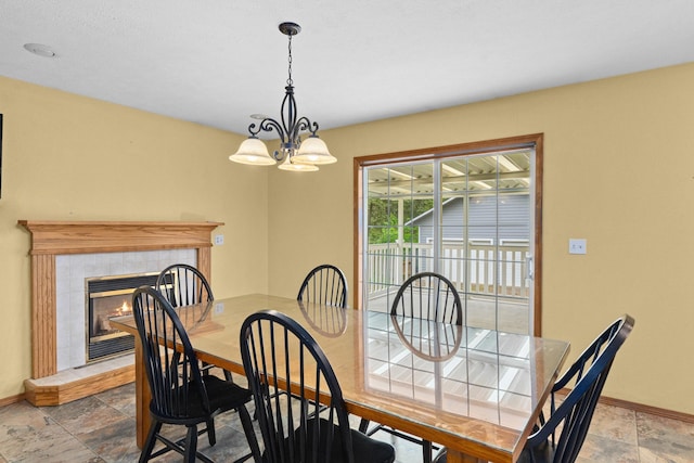 525 Quail Loop, Newport, WA 99156 - dining area with baseboards, a fireplace, stone tile floors, and a chandelier