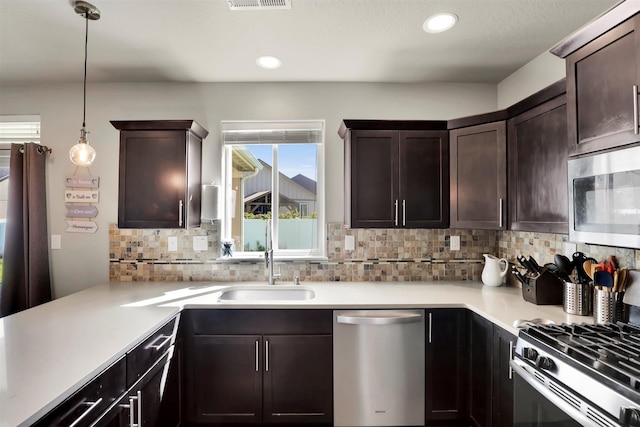 1105 S Oswald St, Spokane, WA 99224 - kitchen featuring appliances with stainless steel finishes, a sink, dark brown cabinets, backsplash, and light countertops