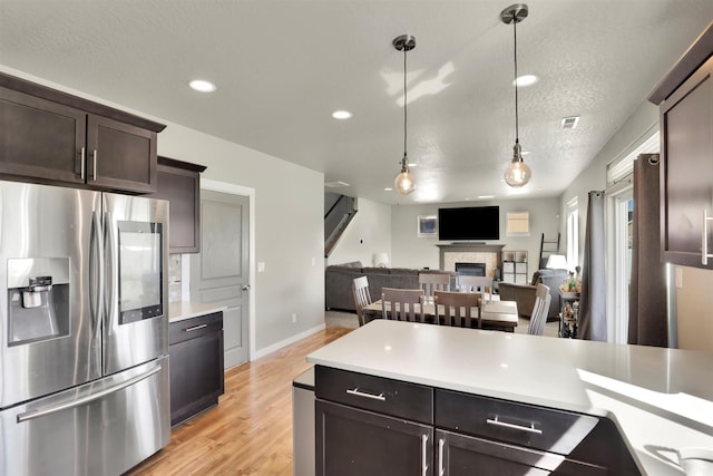 1105 S Oswald St, Spokane, WA 99224 - kitchen featuring stainless steel refrigerator with ice dispenser, dark brown cabinets, light countertops, light wood-type flooring, and a textured ceiling