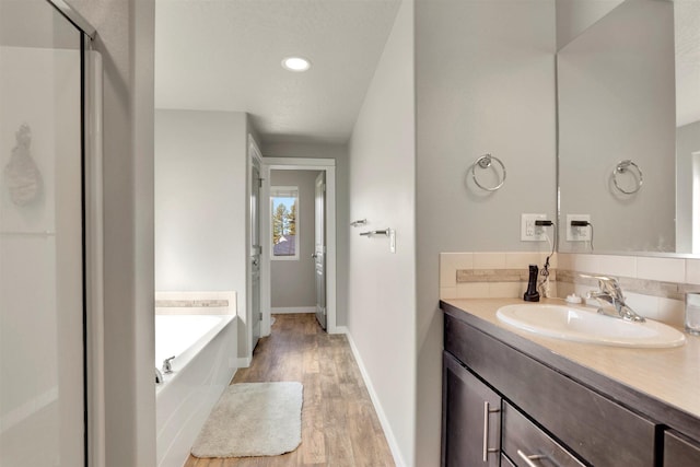 1105 S Oswald St, Spokane, WA 99224 - full bathroom with wood finished floors, a bath, vanity, a stall shower, and baseboards