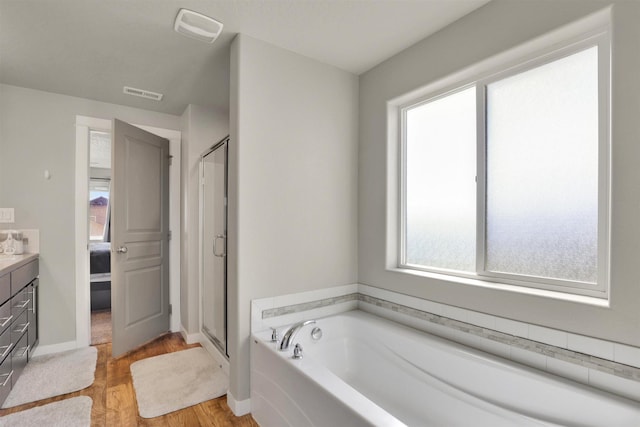 1105 S Oswald St, Spokane, WA 99224 - ensuite bathroom with vanity, a bath, a shower stall, wood finished floors, and baseboards