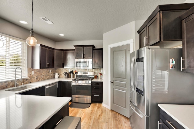 1105 S Oswald St, Spokane, WA 99224 - kitchen featuring stainless steel appliances, a sink, dark brown cabinetry, light wood-style floors, and light countertops