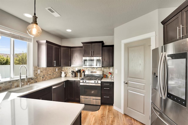1105 S Oswald St, Spokane, WA 99224 - kitchen featuring stainless steel appliances, a sink, dark brown cabinets, backsplash, and light countertops