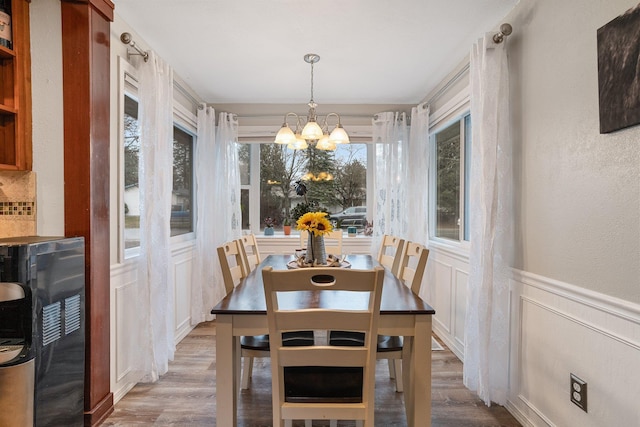 220 W Evergreen Dr, Kettle Falls, WA 99141 - dining area with a chandelier, wood finished floors, a wainscoted wall, a decorative wall, and a textured wall