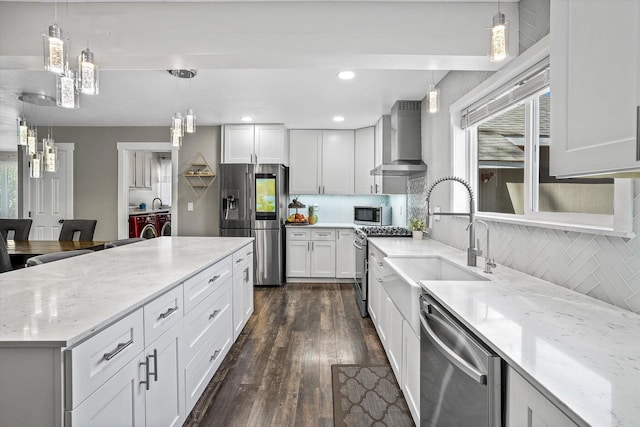 903 E 11th Ave, Spokane, WA 99202 - kitchen featuring washer and clothes dryer, appliances with stainless steel finishes, wall chimney range hood, a sink, and dark wood-type flooring