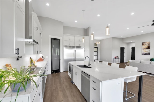 5110 W Hayden Ln, Spokane, WA 99208 - kitchen with appliances with stainless steel finishes, a sink, dark wood-type flooring, a kitchen breakfast bar, and wall chimney exhaust hood