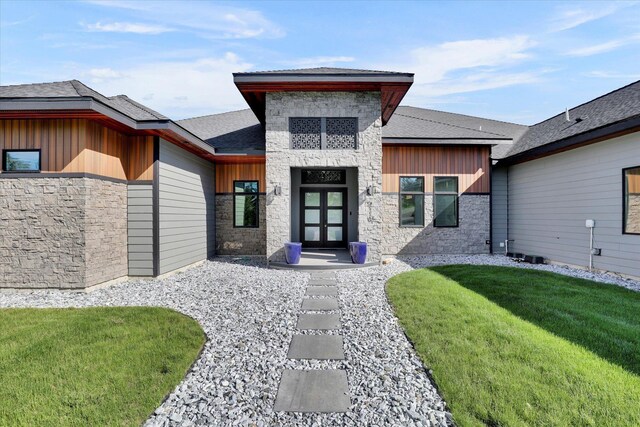 5110 W Hayden Ln, Spokane, WA 99208 - view of exterior entry featuring stone siding, board and batten siding, a lawn, french doors, and roof with shingles