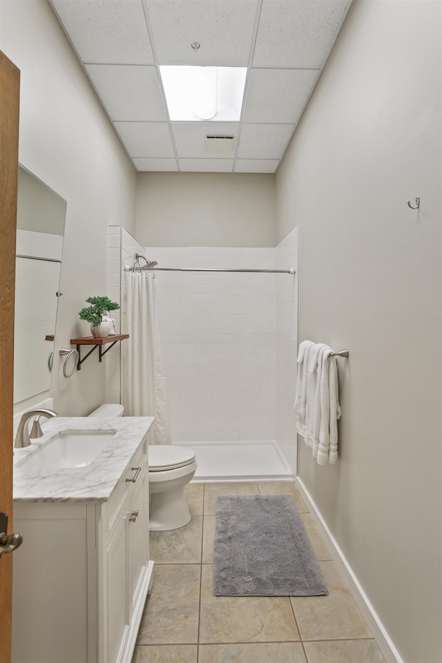 423 W 1st Ave Unit 110, Spokane, WA 99201 - full bathroom with toilet, a paneled ceiling, vanity, a tile shower, and tile patterned flooring