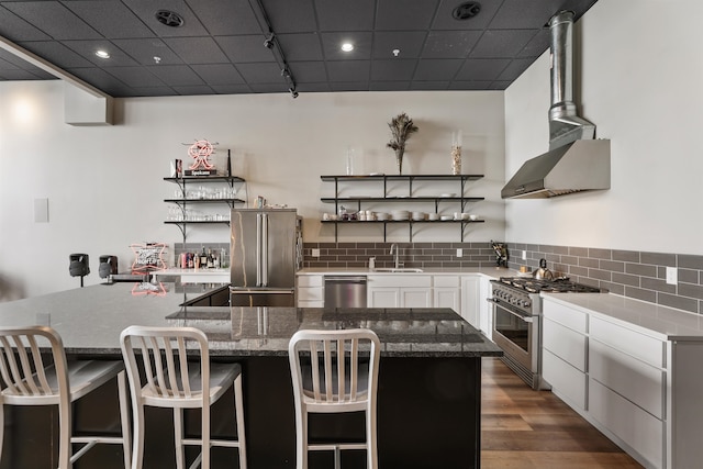 423 W 1st Ave Unit 110, Spokane, WA 99201 - kitchen featuring high end appliances, a sink, open shelves, white cabinets, and wall chimney exhaust hood