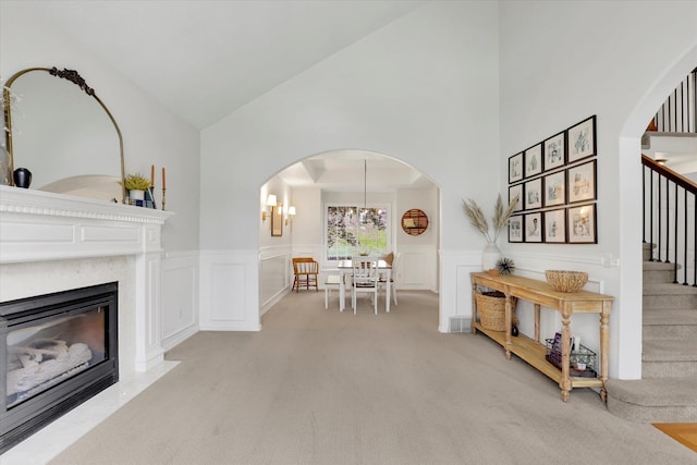 16906 N Golden Dr, Colbert, WA 99005 - carpeted living area featuring arched walkways, stairs, high vaulted ceiling, wainscoting, and a high end fireplace