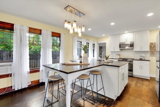 7311 E Fairview Ave, Spokane Valley, WA 99212 - kitchen featuring appliances with stainless steel finishes, dark countertops, dark wood-style flooring, backsplash, and white cabinetry