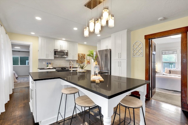 7311 E Fairview Ave, Spokane Valley, WA 99212 - kitchen featuring stainless steel appliances, dark countertops, dark wood finished floors, a breakfast bar area, and recessed lighting