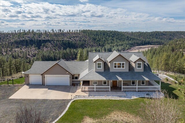 16503 W Bluebird Ln, Spokane, WA 99224 - view of front of property with a forest view, a porch, driveway, an attached garage, and a front yard