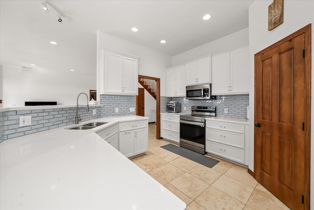 16503 W Bluebird Ln, Spokane, WA 99224 - kitchen with stainless steel appliances, a sink, tasteful backsplash, white cabinets, and light countertops