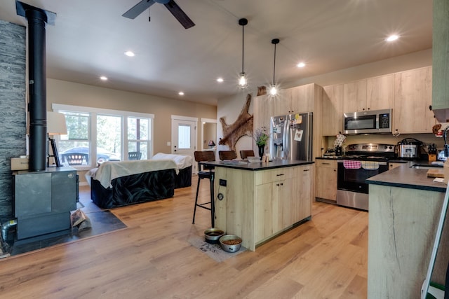 33319 N Conklin Rd, Elk, WA 99009 - kitchen featuring appliances with stainless steel finishes, a wood stove, light brown cabinetry, dark countertops, and recessed lighting