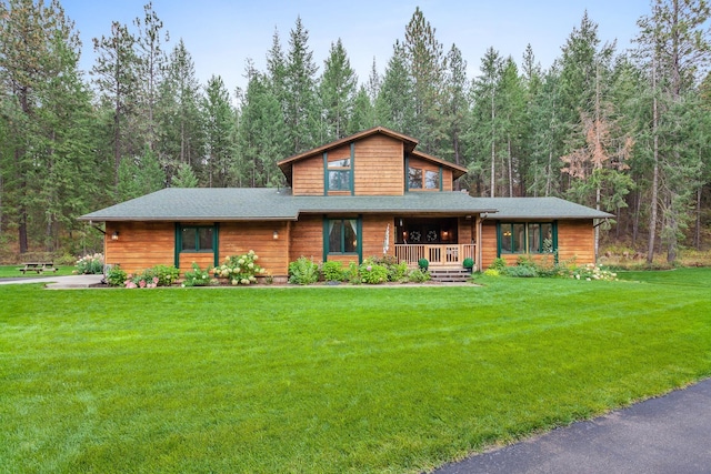 5999 E Roger Dr, Post Falls, ID 83854 - view of front of house with covered porch, a front yard, and a view of trees