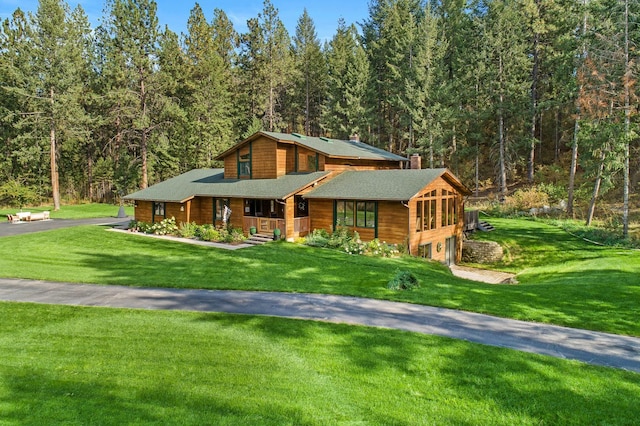 5999 E Roger Dr, Post Falls, ID 83854 - view of front of house featuring a chimney, a garage, driveway, a front lawn, and a forest view