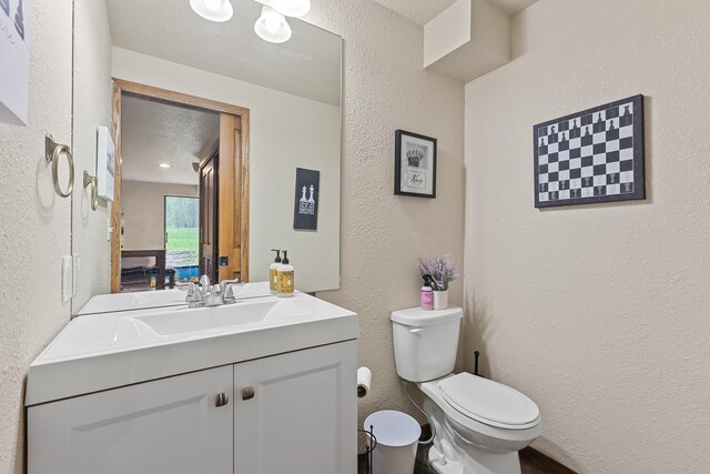 5999 E Roger Dr, Post Falls, ID 83854 - half bathroom featuring a textured wall, vanity, and toilet